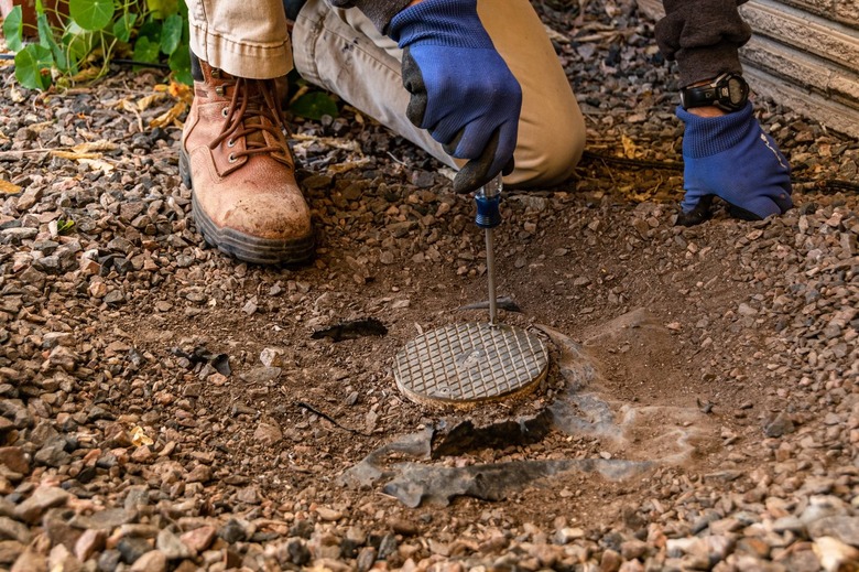 sewer drain cleaning removing screws on outdoor sewer drain cleanout cover