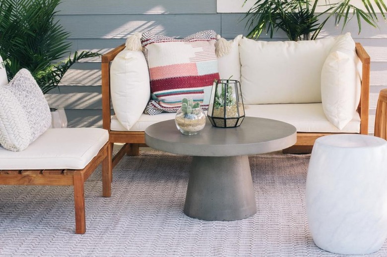 relaxing indoor outdoor setup with boho furniture and round concrete table with terrariums
