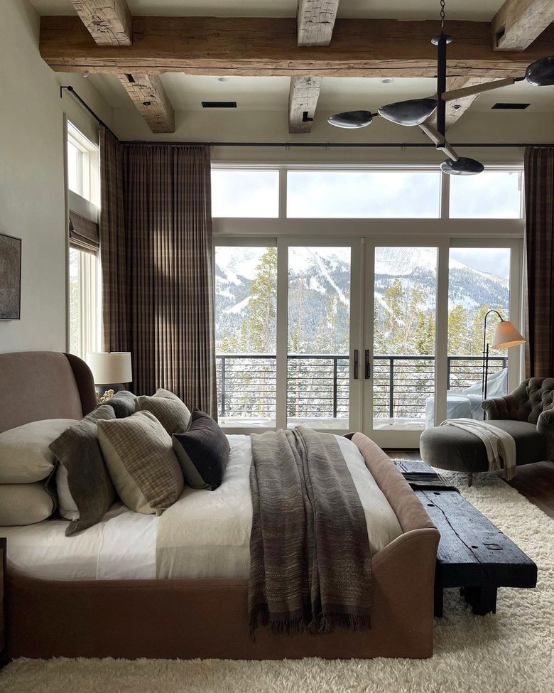 Cozy mountain bedroom with wooden beams and wide window