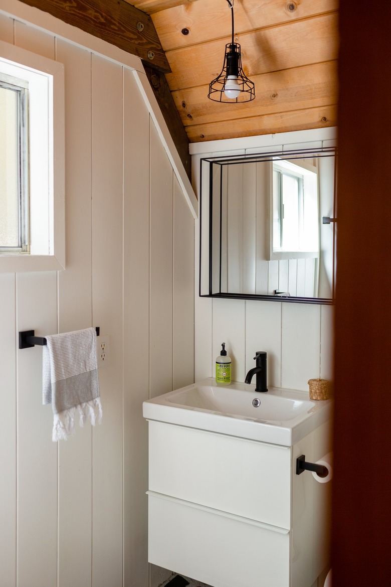 White-walled bathroom with wood ceiling with mirror