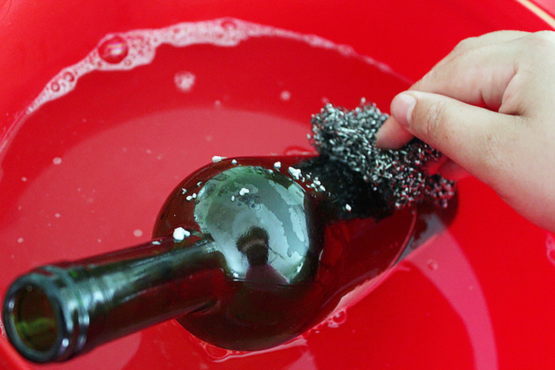 Gently scrub the glue and paper off the bottle with steel wool.