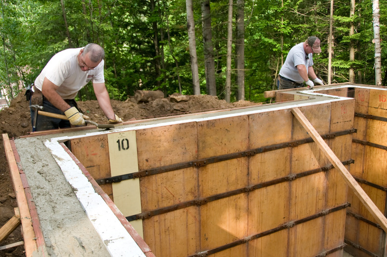 Two construction workers smoothing concrete in wall molds