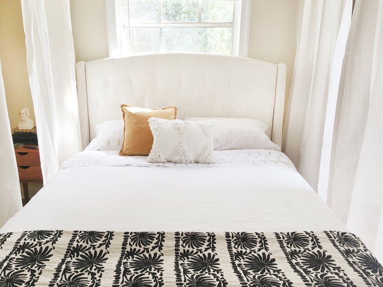 a bed with curtains hanging from the ceiling around it to create a canopy