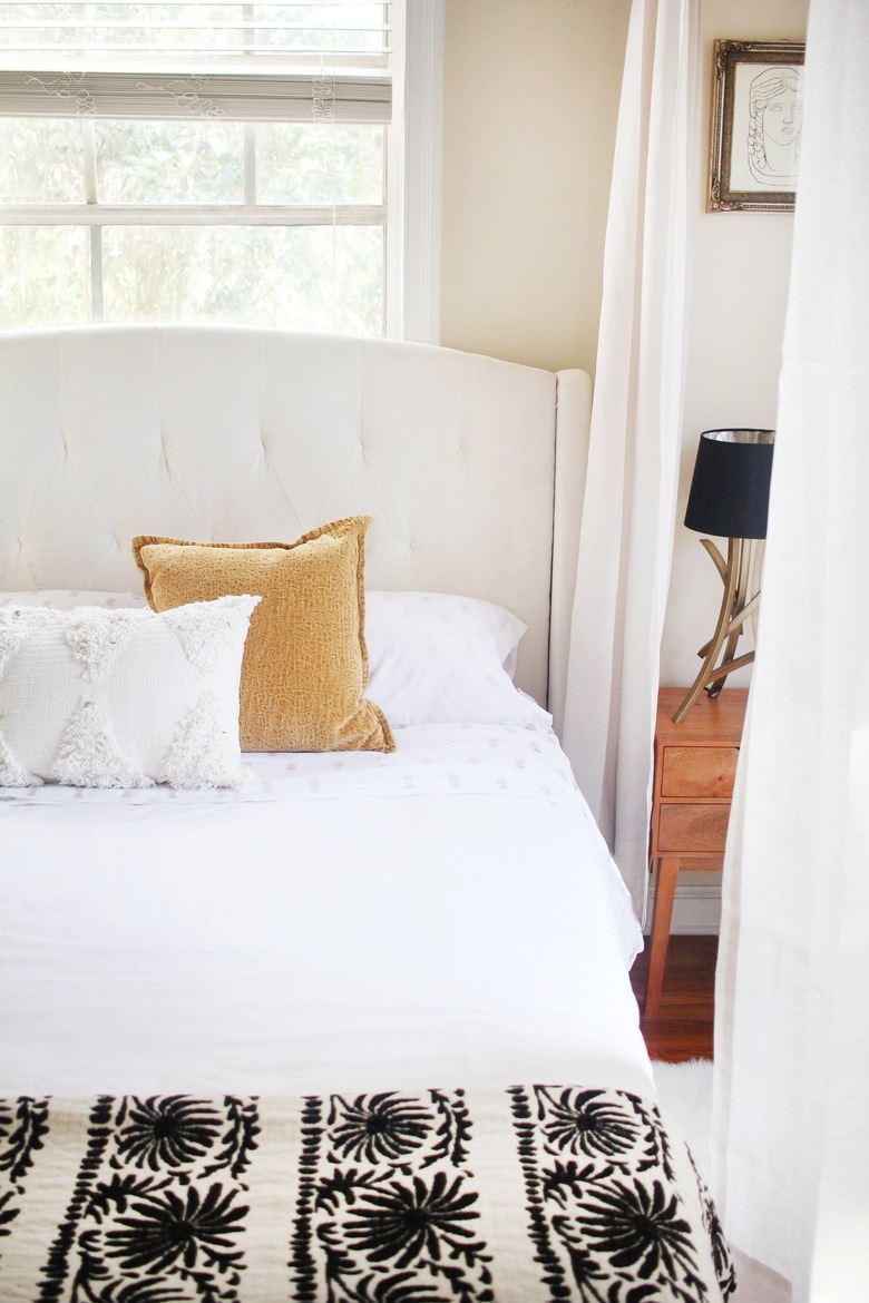 a bed with curtains hanging from the ceiling around it to create a canopy