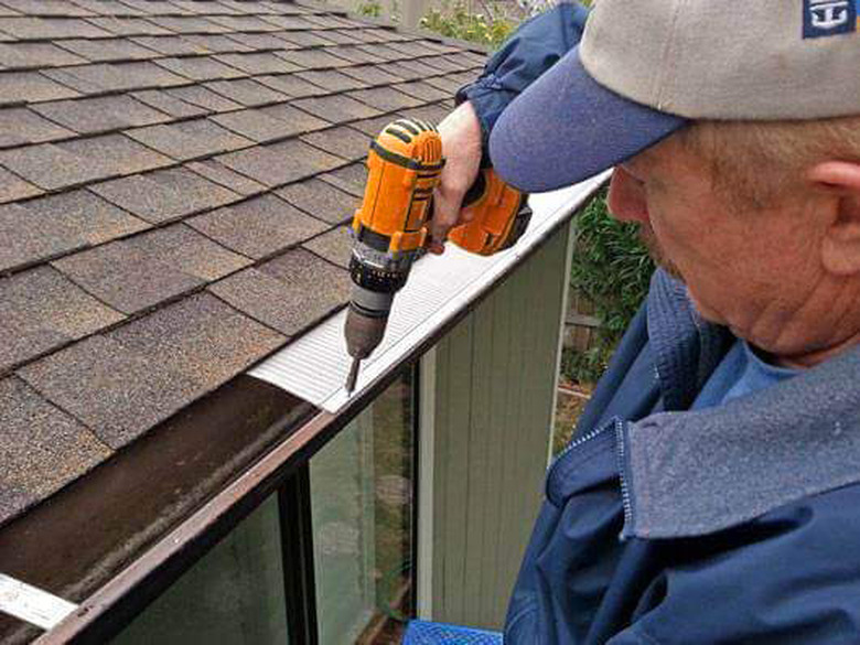 Contractor attaching gutter guard to gutter.
