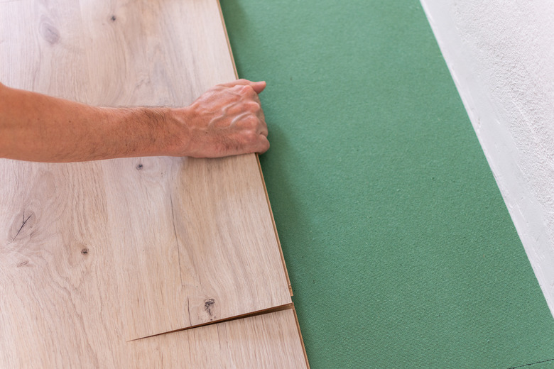 Worker installing wooden laminate flooring