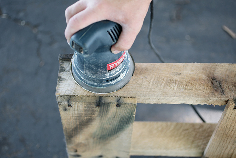 Orbital sander sanding piece of wood.