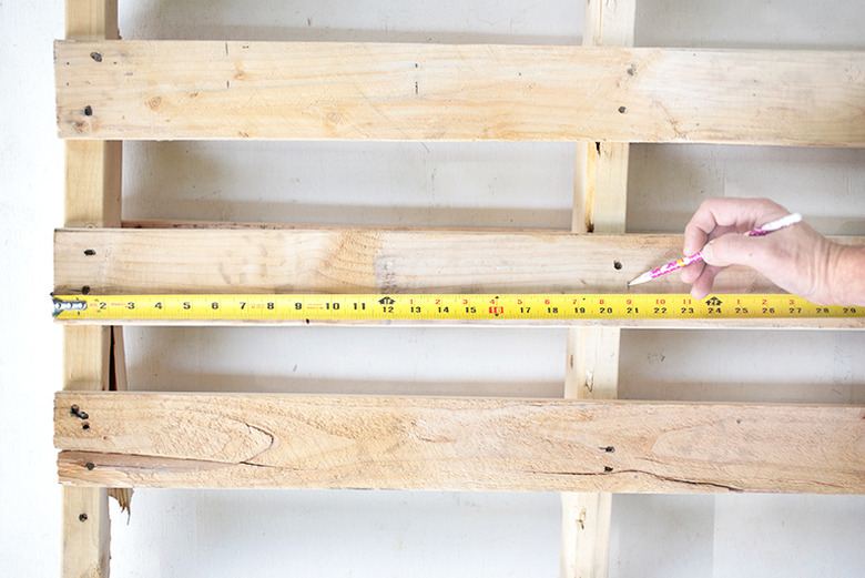 Pallet wood with measuring tape and hand marking measurement.