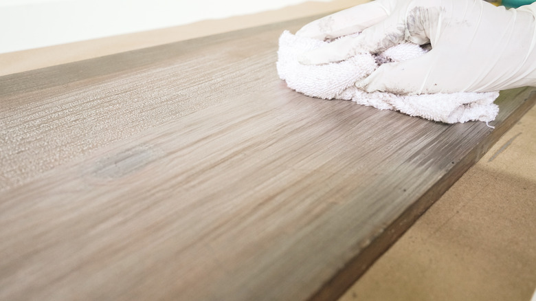 Blending whitewash with rag for faux weathered wood finish.