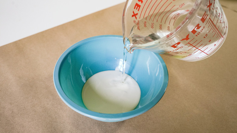 Mixing whitewash for faux weathered wood finish.