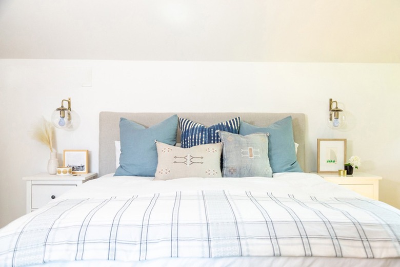 Linen upholstered headboard of a bed with blue and gray pillows