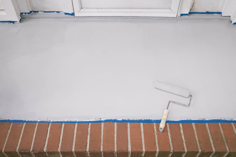 Rolling gray paint onto the concrete porch