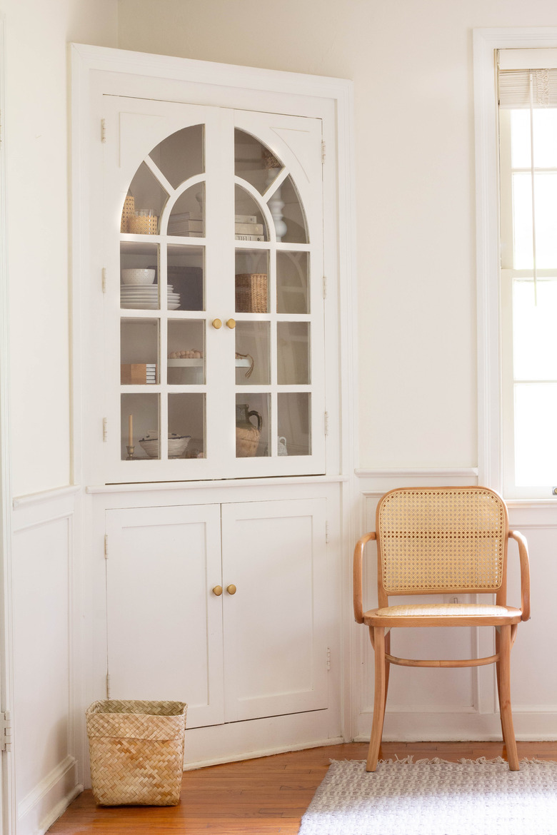 White corner cabinet with glass doors and brass hardware