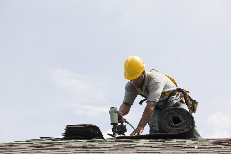 Roofer working on shingling a new roof