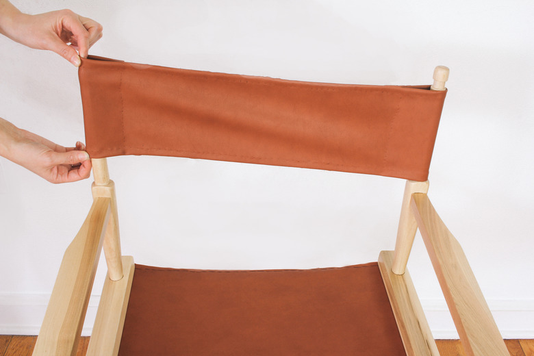 Sliding new chair back cover onto poles of chair