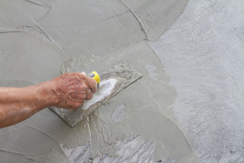 Hand using trowel on fresh concrete in construction site