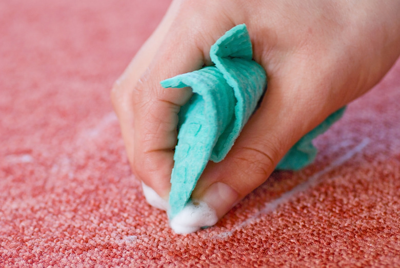 cleaning red carpet floor with rag and hand