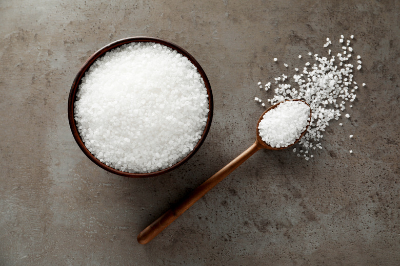 Bowl and spoon with natural sea salt on grey table