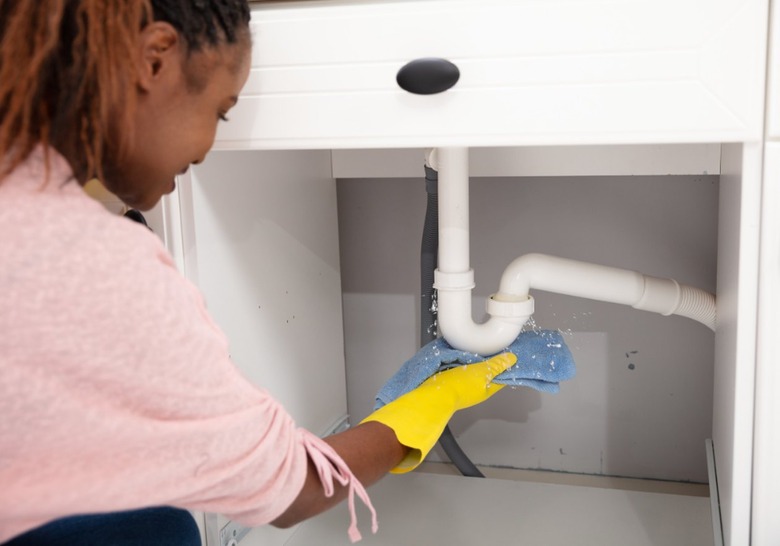 woman checking for leaks underneath sink