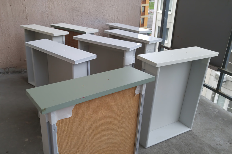 Painting the drawers of the cabinet and the bedside tables from the paint can. In white color. On the balcony.