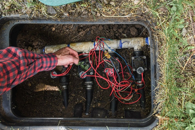 inspecting and cleaning sprinkler system valve in valve box