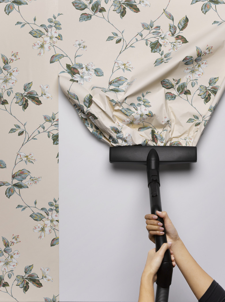 Woman vacuuming wallpaper from wall