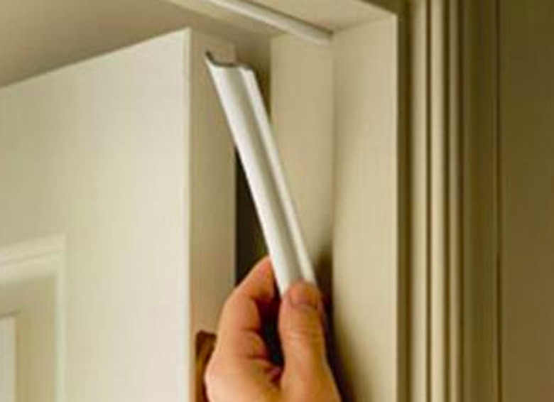 Installing weather stripping on door frame.