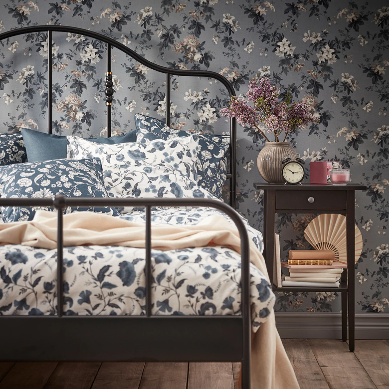 bedroom with floral wallpaper and floral sheets and black night stand