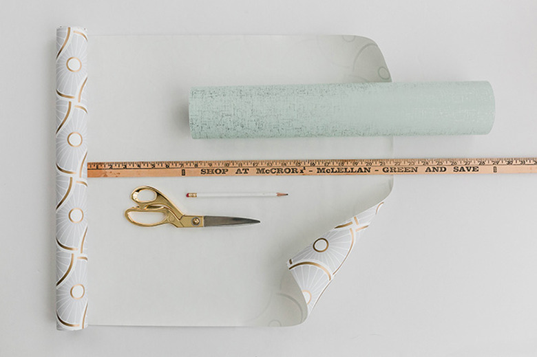 Measure and mark pieces of wallpaper for the sides and front of the cabinet.
