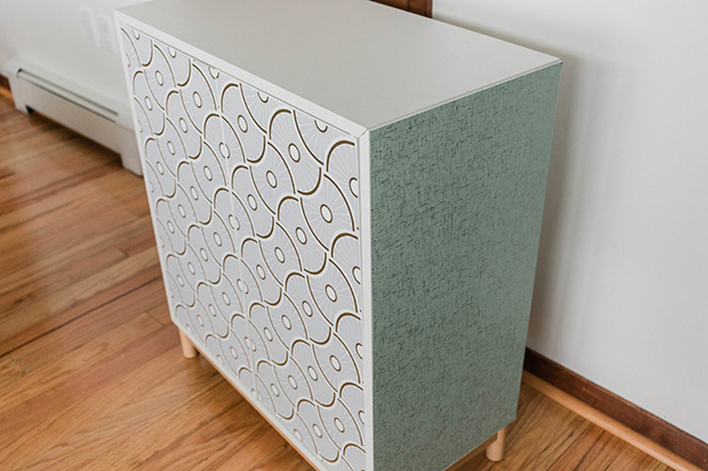 Attach the wallpaper pieces to the front and sides of the cabinet.