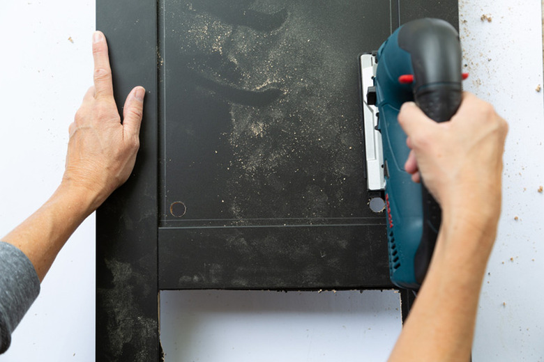 Jigsaw cutting out black panel on an IKEA cabinet