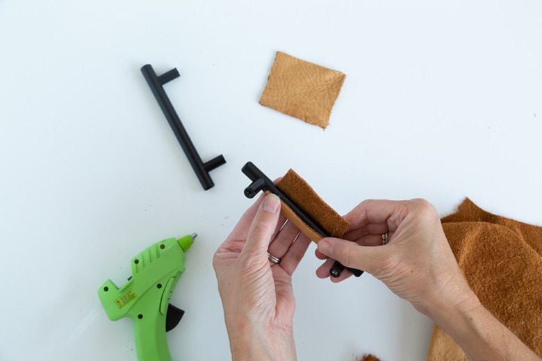 Attaching leather scraps to black cabinet handles