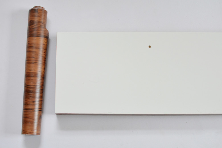 underside of white shelf and roll of brown contact paper