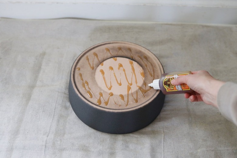 A hand piping glue onto the bottom of planter