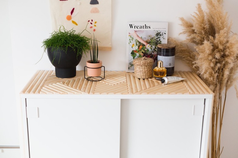White dresser with wooden dowel pattern with plants