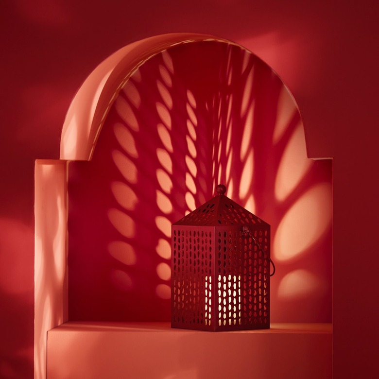 A red lantern sitting on a red platform in front of a red wall.