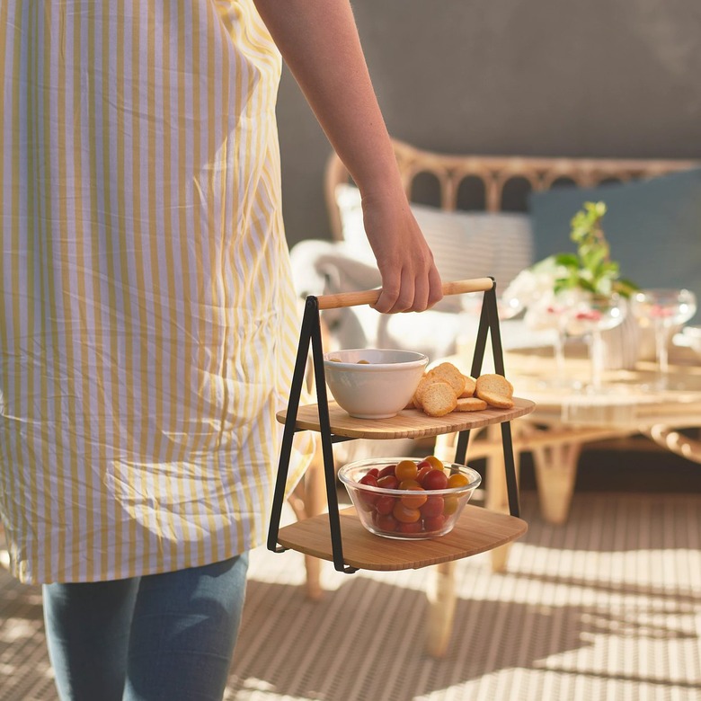person holding bamboo tray with dishes with food