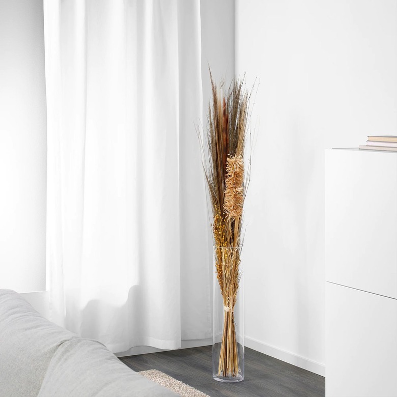 dried florals in vase near white curtain and dresser