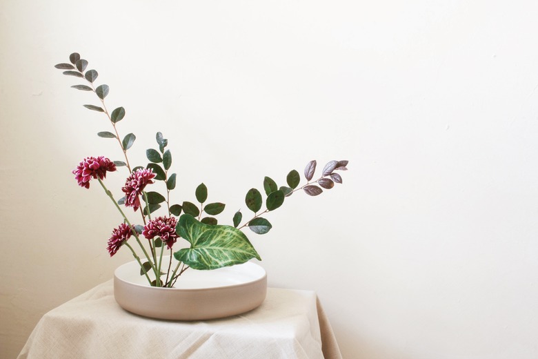 diy ikebana flower arrangement of burgundy flowers and long green leaves
