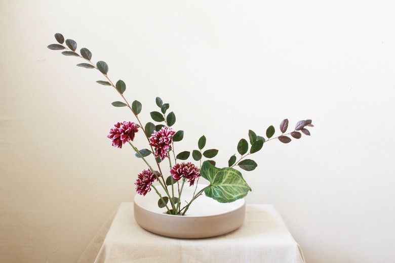 large green leaf inserted into ikebana flower arrangement