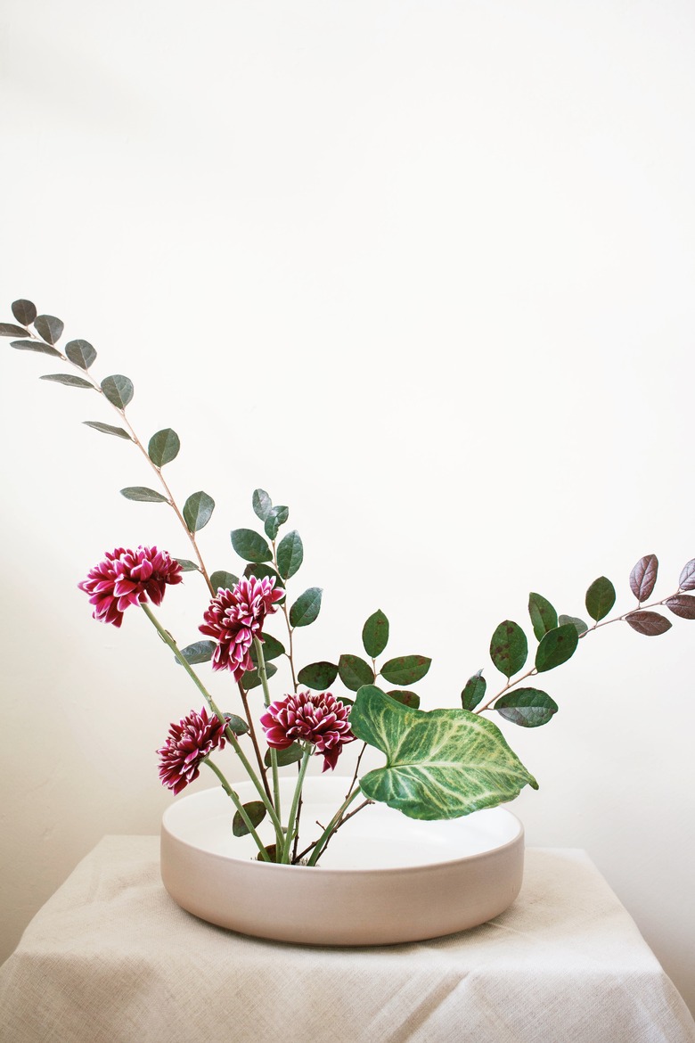 diy ikebana arrangement with burgundy flowers and green leaves