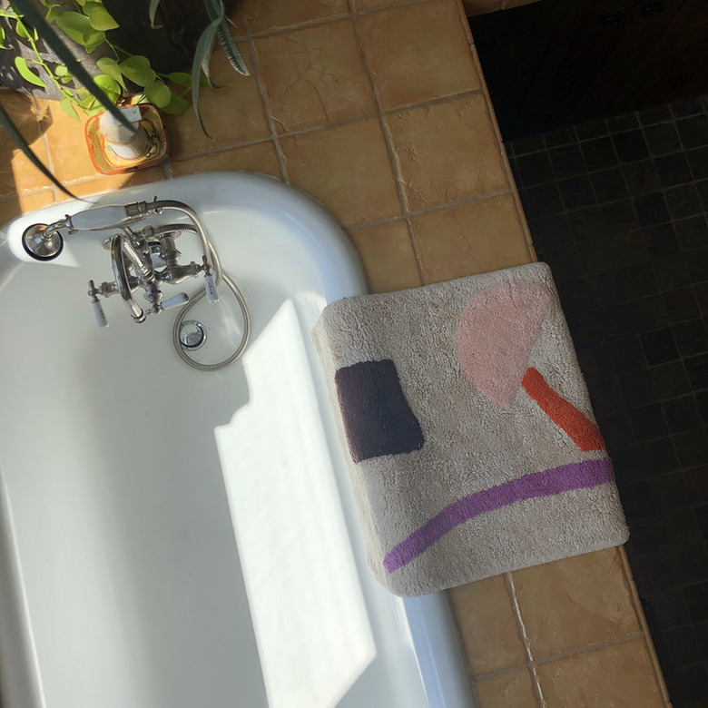 bathtub seen from above with graphic bathmat nearby