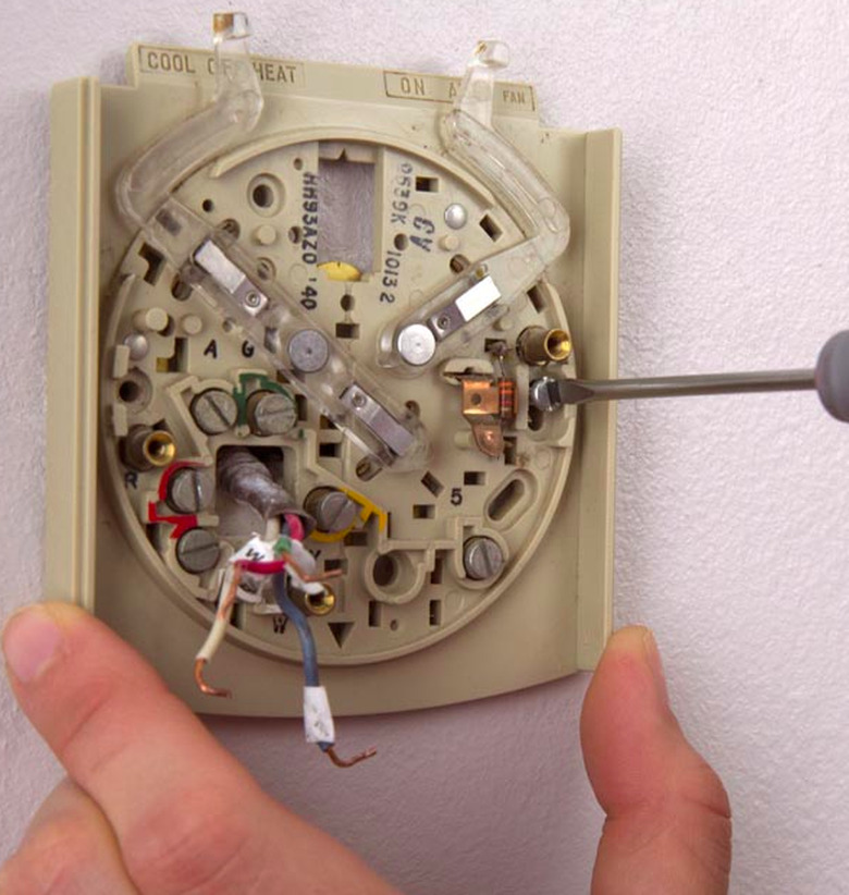Thermostat being unscrewed.