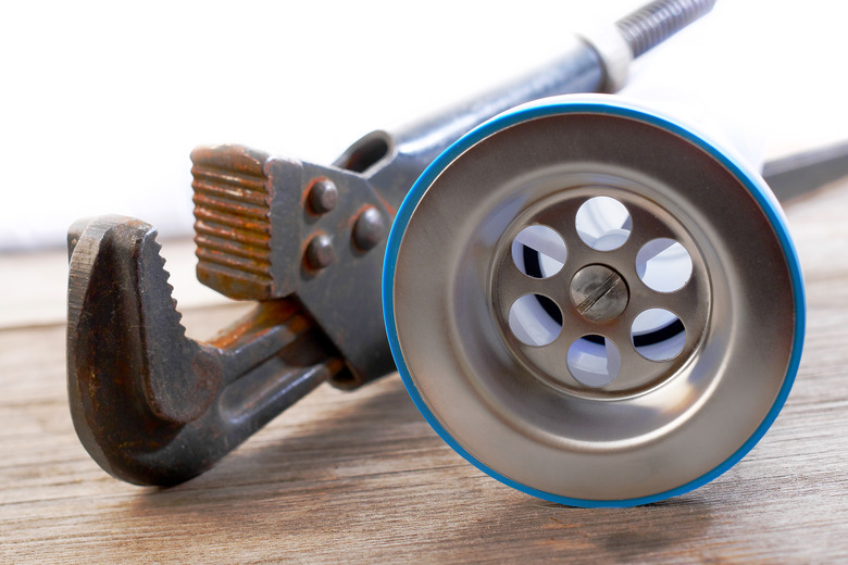 closeup of kitchen drain assembly and adjustable plumber wrench