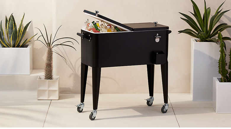 black rolling cooler with ice and wine bottles in a tropical outdoor setting