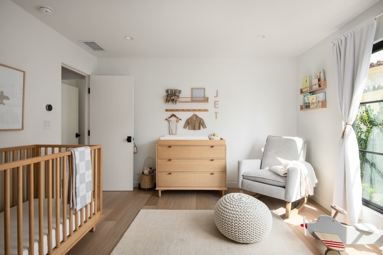 A Scandinavian nursery with a wood crib and dresser