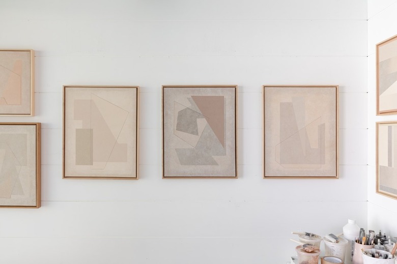 Canvases with neutral geometric shapes hanging on a white wall
