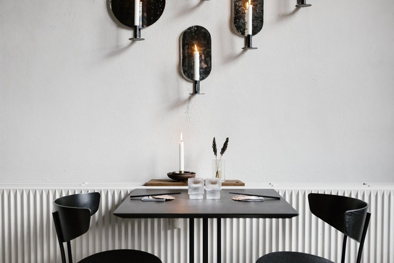 Black dining furniture next to radiator under wall with candle sconces