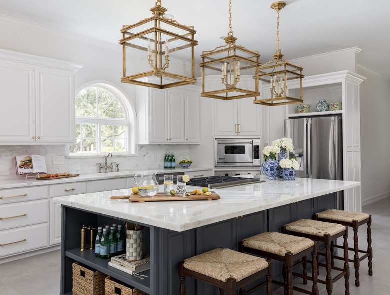 White kitchen with deep blue gray island and gold pendant lights