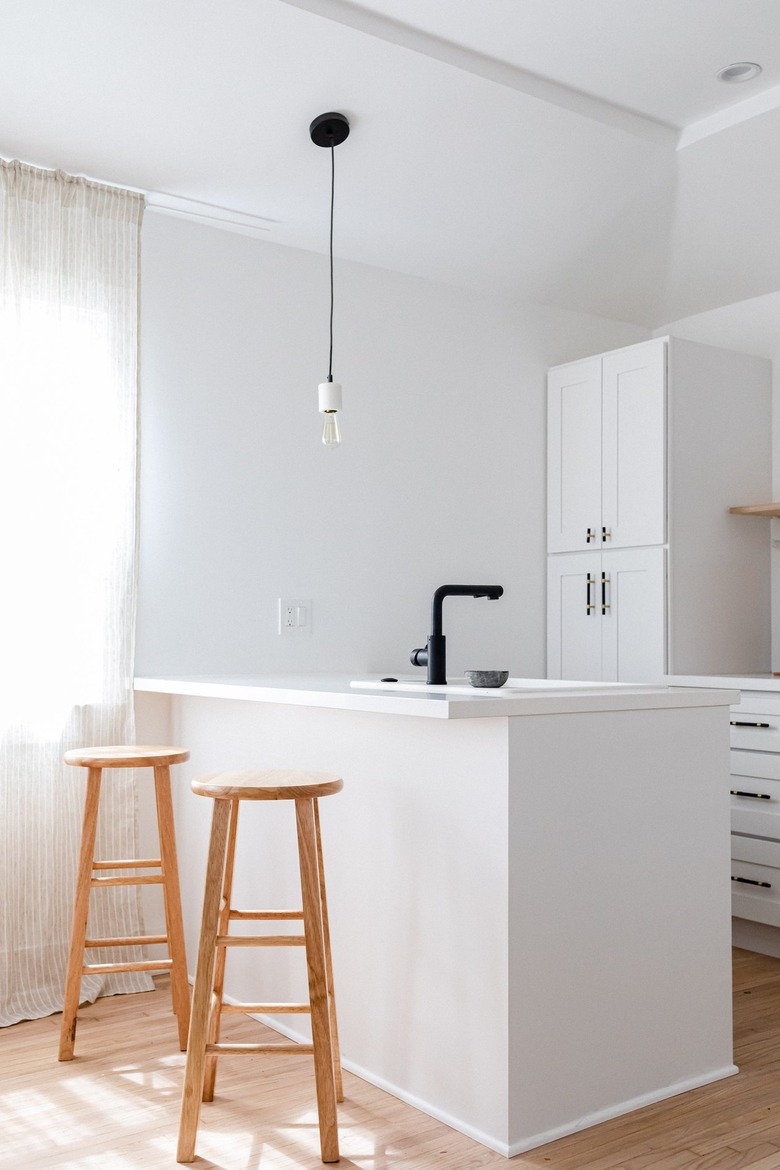 White kitchen island and cabinets with black accents and wood floors